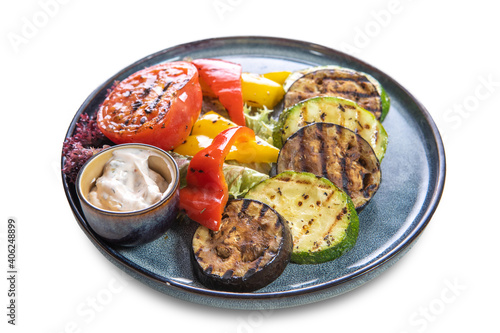 Grilled vegetables: eggplant, tomatoes, bell peppers and sauce on plates on a white isolated background. The view from the top.