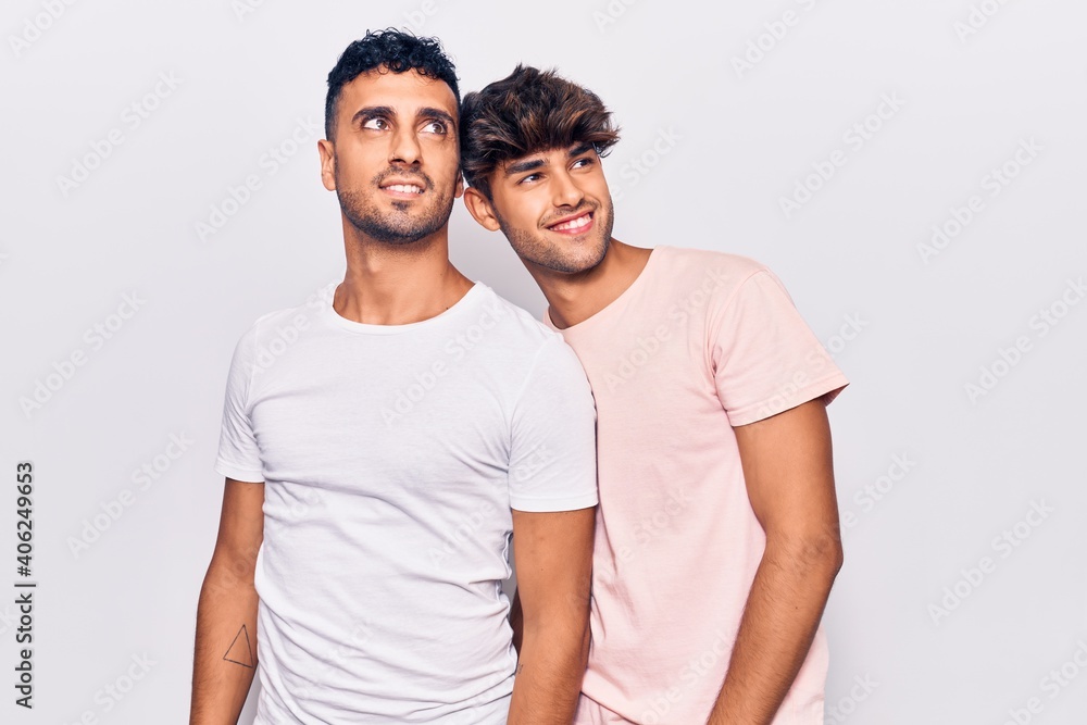 Young gay couple wearing casual clothes looking away to side with smile on face, natural expression. laughing confident. Young gay couple wearing casual clothes looking away to side with smile on face, natural expression. laughing confident.