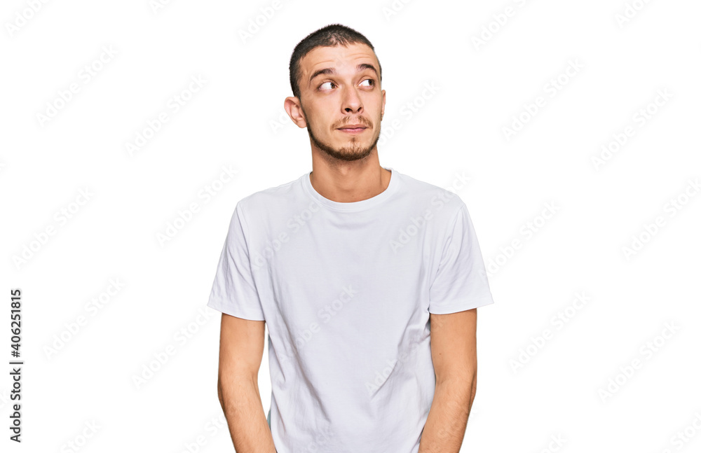 Obraz premium Hispanic young man wearing casual white t shirt smiling looking to the side and staring away thinking.