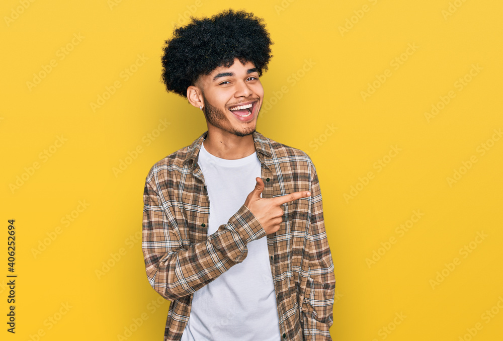Young african american man with afro hair wearing casual clothes cheerful with a smile of face pointing with hand and finger up to the side with happy and natural expression on face Young african american man with afro hair wearing casual clothes cheerful with a smile of face pointing with hand and finger up to the side with happy and natural expression on face