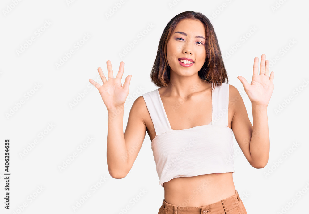 Young beautiful chinese girl wearing casual clothes showing and pointing up with fingers number ten while smiling confident and happy. Young beautiful chinese girl wearing casual clothes showing and pointing up with fingers number ten while smiling confident and happy.