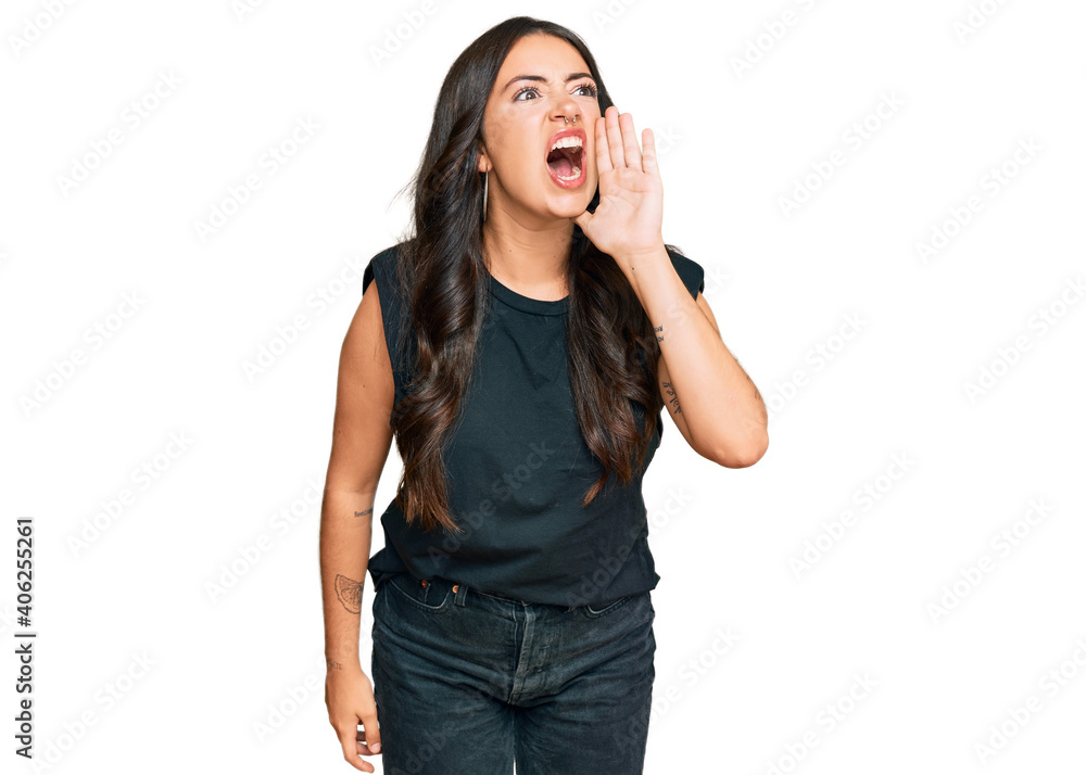 Beautiful brunette young woman wearing black shirt shouting and screaming loud to side with hand on mouth. communication concept.