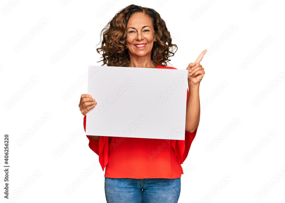 Middle age hispanic woman holding blank empty banner smiling happy pointing with hand and finger to the side Middle age hispanic woman holding blank empty banner smiling happy pointing with hand and finger to the side