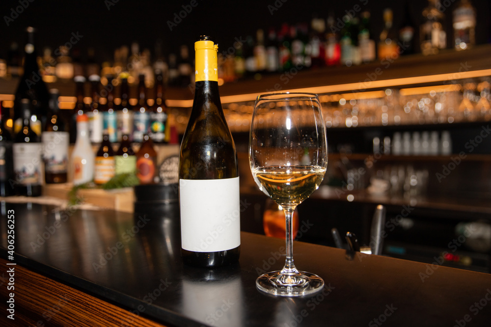 Portrait of a glass of white wine and bottle in a bar