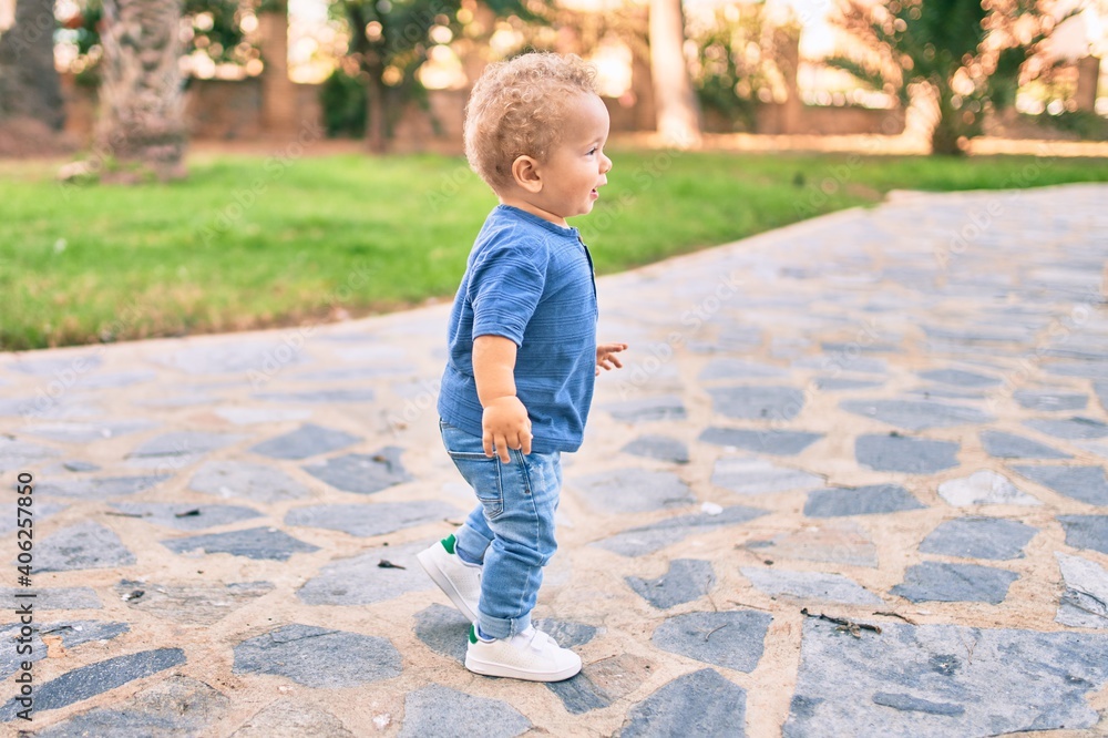 Cute and happy little boy having fun at the park on a sunny day. Beautiful blonde hair male toddler playing outdoors