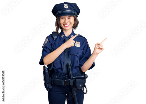 Young beautiful girl wearing police uniform smiling and looking at the camera pointing with two hands and fingers to the side.