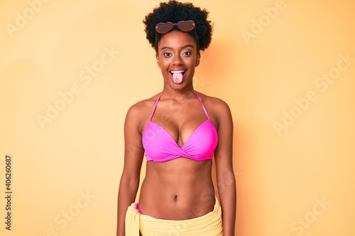 Young african american woman wearing bikini sticking tongue out happy with funny expression. emotion concept.