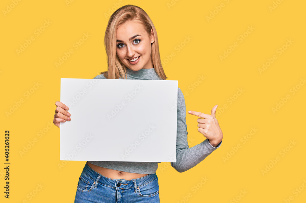 Naklejka premium Beautiful caucasian woman holding blank empty banner smiling happy pointing with hand and finger