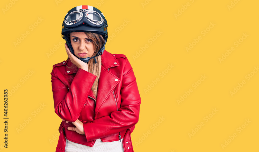 Young beautiful woman wearing motorcycle helmet thinking looking tired and bored with depression problems with crossed arms. Young beautiful woman wearing motorcycle helmet thinking looking tired and bored with depression problems with crossed arms.