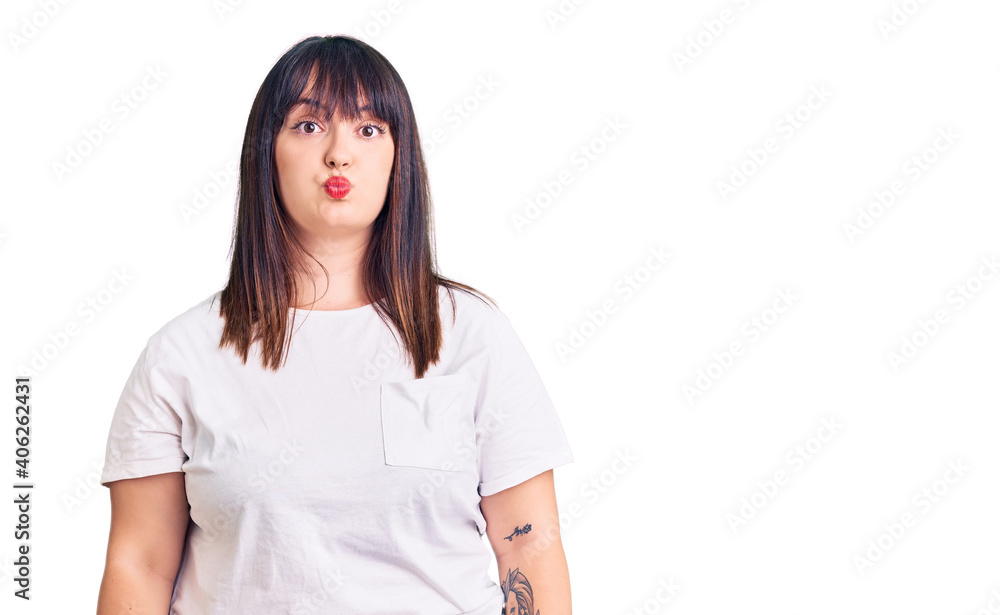 Young plus size woman wearing casual clothes puffing cheeks with funny face. mouth inflated with air, crazy expression. Young plus size woman wearing casual clothes puffing cheeks with funny face. mouth inflated with air, crazy expression.
