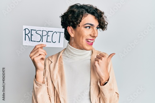 Obraz na plátně Young man wearing woman make up and woman clothes holding respect banner pointin