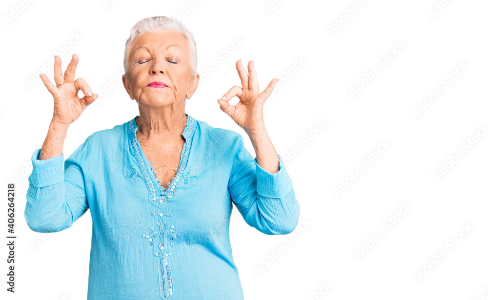 Senior beautiful woman with blue eyes and grey hair wearing summer dress relax and smiling with eyes closed doing meditation gesture with fingers. yoga concept. Senior beautiful woman with blue eyes and grey hair wearing summer dress relax and smiling with eyes closed doing meditation gesture with fingers. yoga concept.