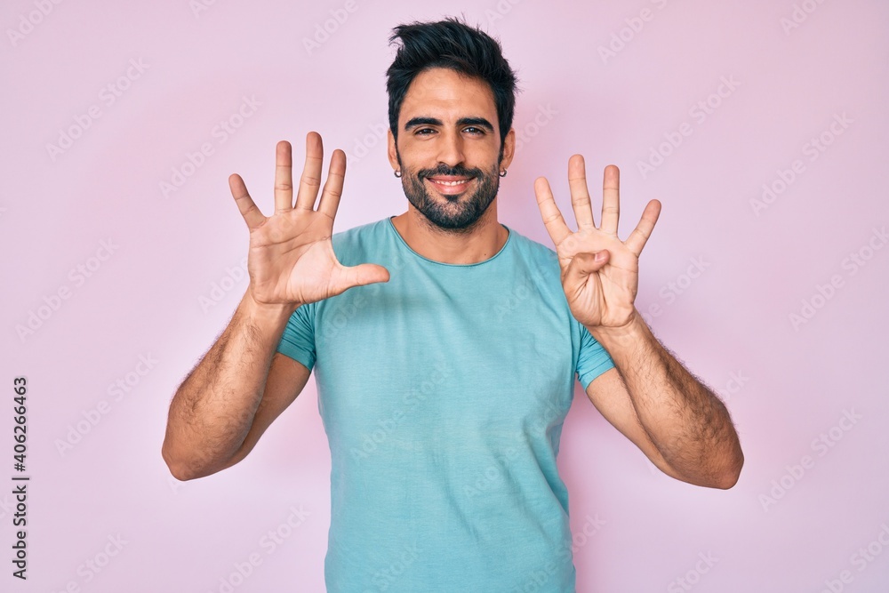 Fototapeta premium Handsome hispanic man with beard wearing casual clothes showing and pointing up with fingers number nine while smiling confident and happy.