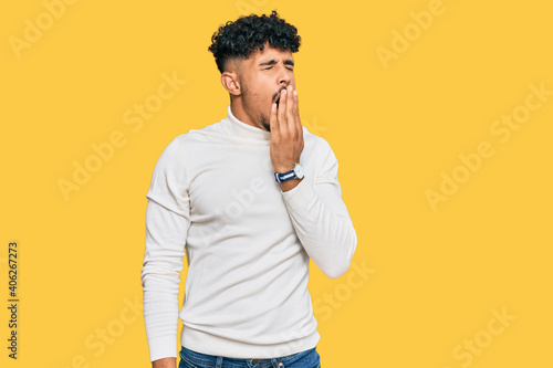Young arab man wearing casual winter sweater bored yawning tired covering mouth with hand. restless and sleepiness.