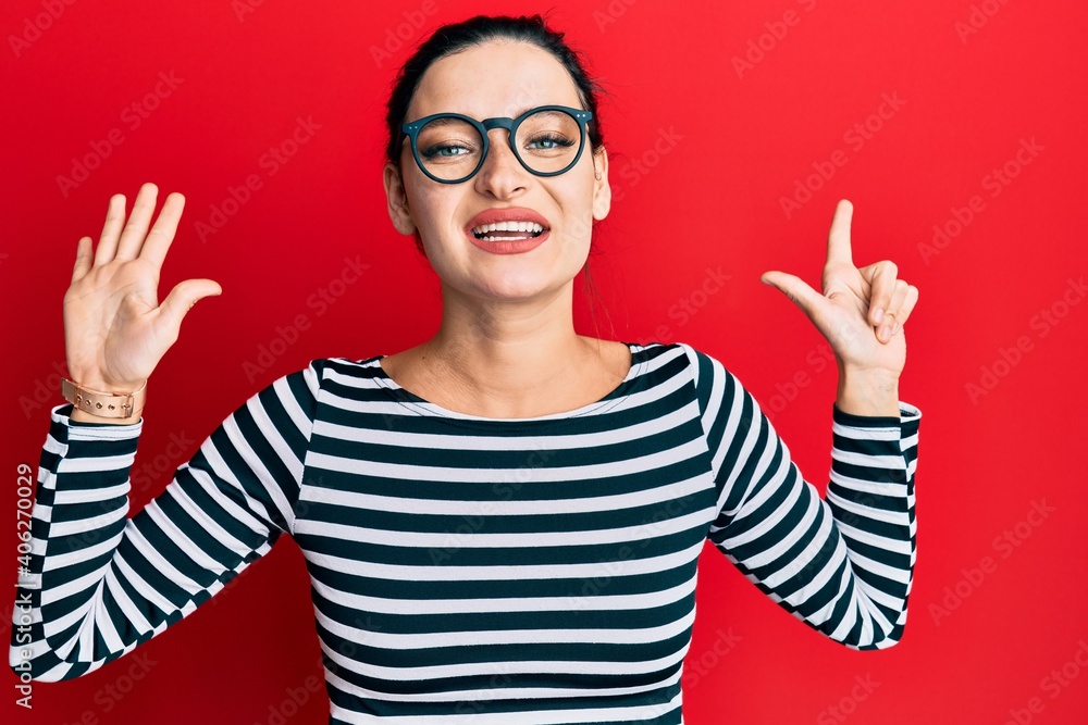 Young caucasian woman wearing casual clothes and glasses showing and pointing up with fingers number seven while smiling confident and happy. Young caucasian woman wearing casual clothes and glasses showing and pointing up with fingers number seven while smiling confident and happy.