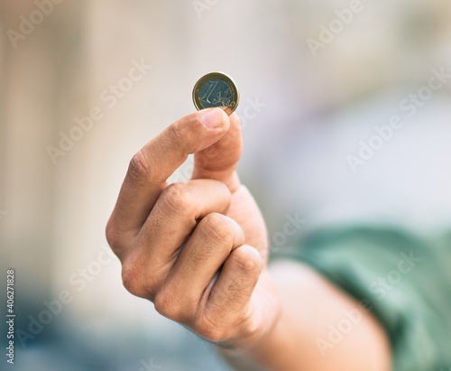 Hand of hispanic man showing one euro coin at the city.