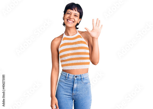 Young brunette woman with short hair wearing casual clothes showing and pointing up with fingers number five while smiling confident and happy.