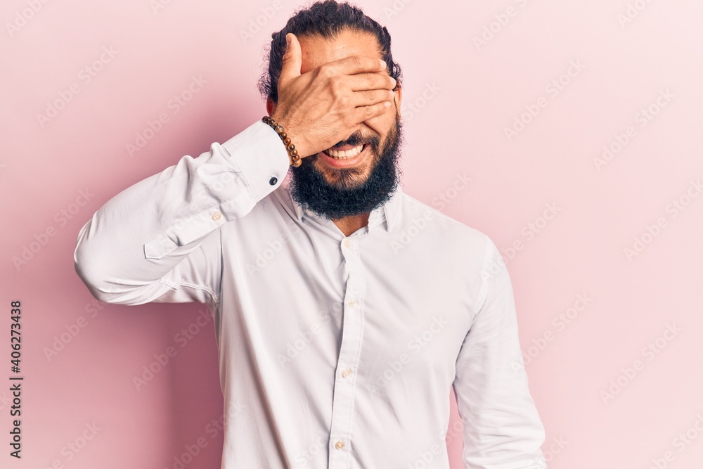 Young arab man wearing casual clothes smiling and laughing with hand on face covering eyes for surprise. blind concept. Young arab man wearing casual clothes smiling and laughing with hand on face covering eyes for surprise. blind concept.