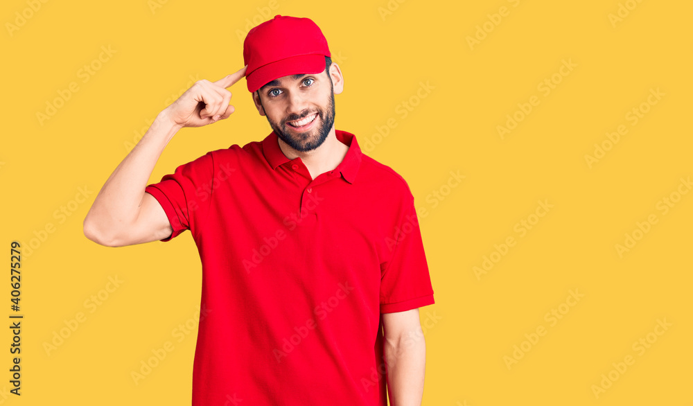 Young handsome man with beard wearing delivery uniform smiling pointing to head with one finger, great idea or thought, good memory