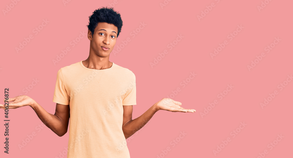 Young african american man wearing casual clothes clueless and confused expression with arms and hands raised. doubt concept. Young african american man wearing casual clothes clueless and confused expression with arms and hands raised. doubt concept.