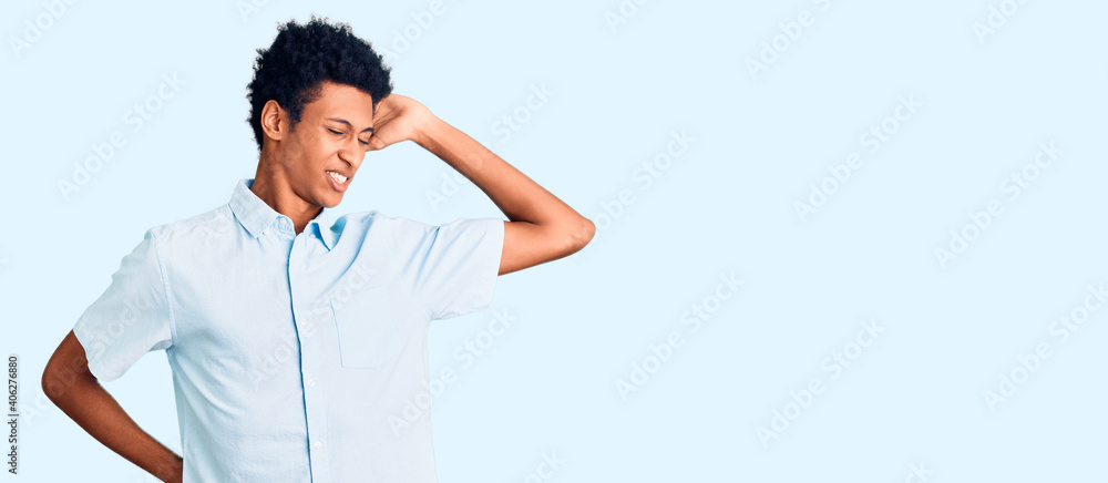 Obraz premium Young african american man wearing casual clothes stretching back, tired and relaxed, sleepy and yawning for early morning