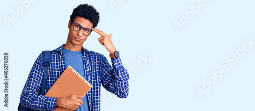 Slika na platnu Young african american man wearing student backpack holding book shooting and killing oneself pointing hand and fingers to head like gun, suicide gesture