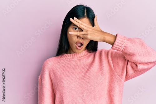 Young chinese woman wearing casual clothes peeking in shock covering face and eyes with hand, looking through fingers afraid © Krakenimages.com
