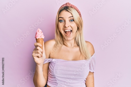 Young caucasian woman holding ice cream celebrating crazy and amazed for success with open eyes screaming excited.