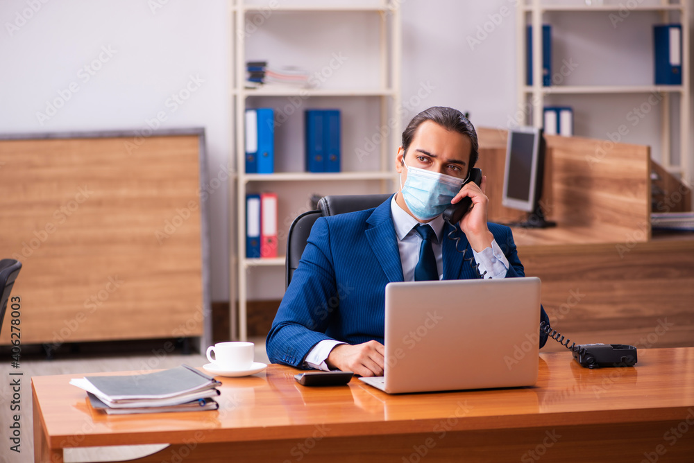 Young male employee working in the office wearing mask Young male employee working in the office wearing mask