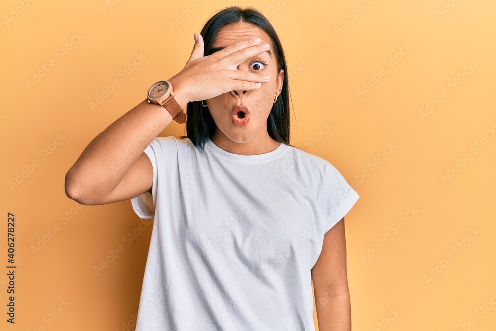 Young asian woman wearing casual white t shirt peeking in shock covering face and eyes with hand, looking through fingers afraid Young asian woman wearing casual white t shirt peeking in shock covering face and eyes with hand, looking through fingers afraid