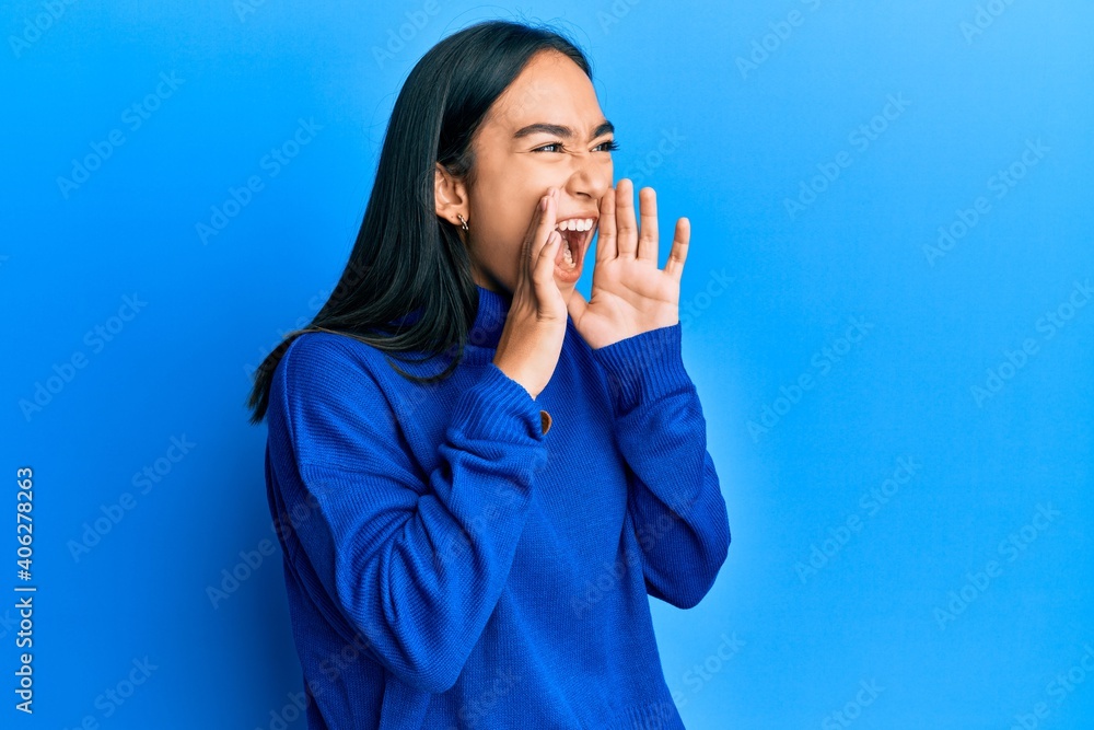 Young asian woman wearing casual winter sweater shouting angry out loud with hands over mouth Young asian woman wearing casual winter sweater shouting angry out loud with hands over mouth