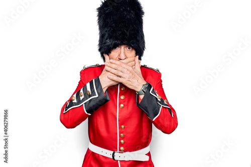 Middle age handsome wales guard man wearing traditional uniform over white background shocked covering mouth with hands for mistake. Secret concept.