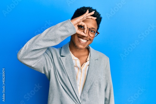 Young african american girl wearing business jacket and glasses smiling happy doing ok sign with hand on eye looking through fingers © Krakenimages.com