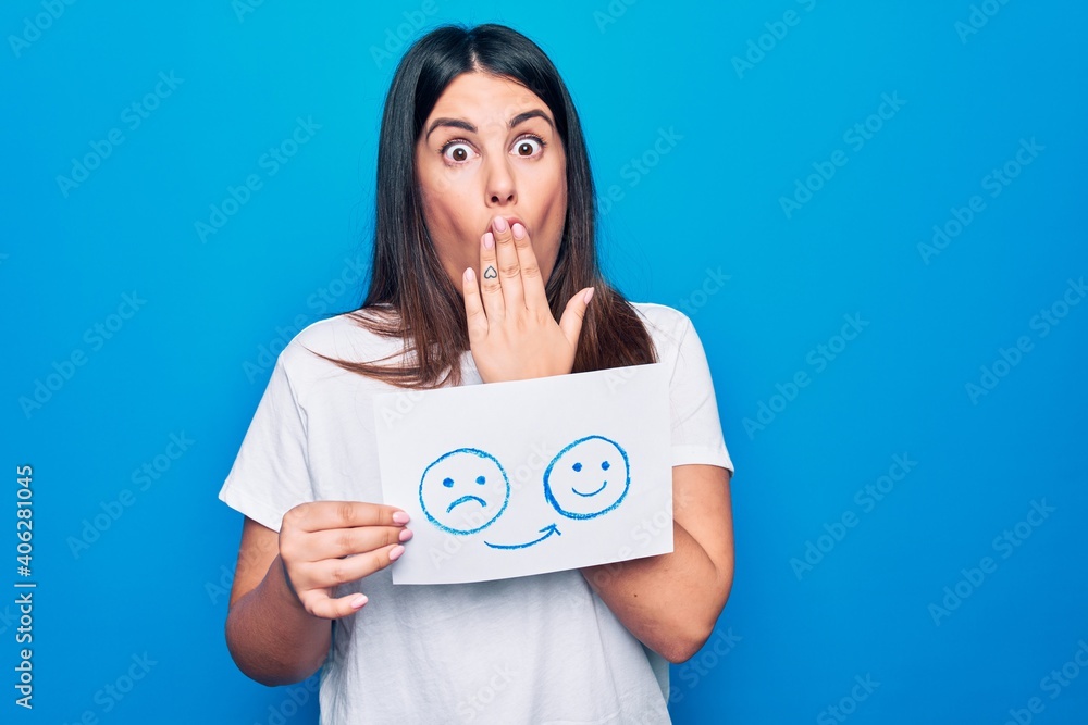 Woman asking for psychology change holding paper with unhappy to happy emotion message covering mouth with hand, shocked and afraid for mistake. Surprised expression Woman asking for psychology change holding paper with unhappy to happy emotion message covering mouth with hand, shocked and afraid for mistake. Surprised expression