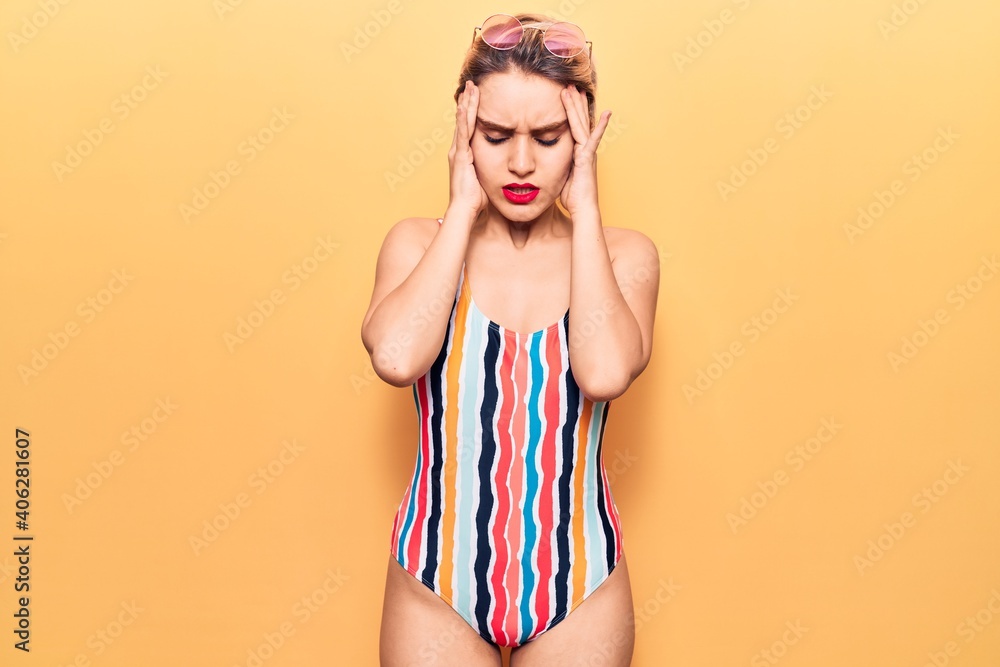 Young beautiful blonde woman wearing swimwear suffering from headache desperate and stressed because pain and migraine. hands on head. Young beautiful blonde woman wearing swimwear suffering from headache desperate and stressed because pain and migraine. hands on head.