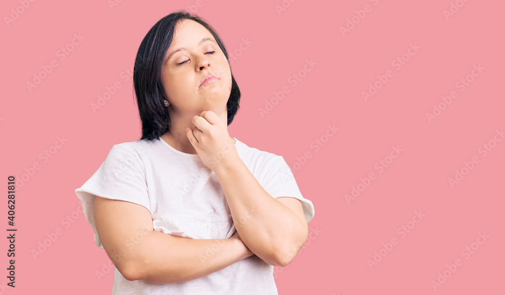 Brunette woman with down syndrome wearing casual white tshirt with hand on chin thinking about question, pensive expression. smiling with thoughtful face. doubt concept. Brunette woman with down syndrome wearing casual white tshirt with hand on chin thinking about question, pensive expression. smiling with thoughtful face. doubt concept.