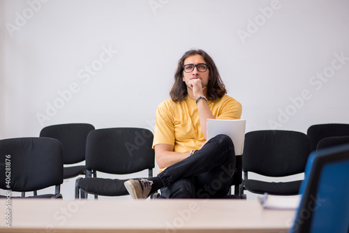 Young male student waiting for teacher in the classroom