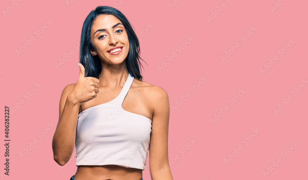 Beautiful hispanic woman wearing casual clothes doing happy thumbs up gesture with hand. approving expression looking at the camera showing success. Beautiful hispanic woman wearing casual clothes doing happy thumbs up gesture with hand. approving expression looking at the camera showing success.