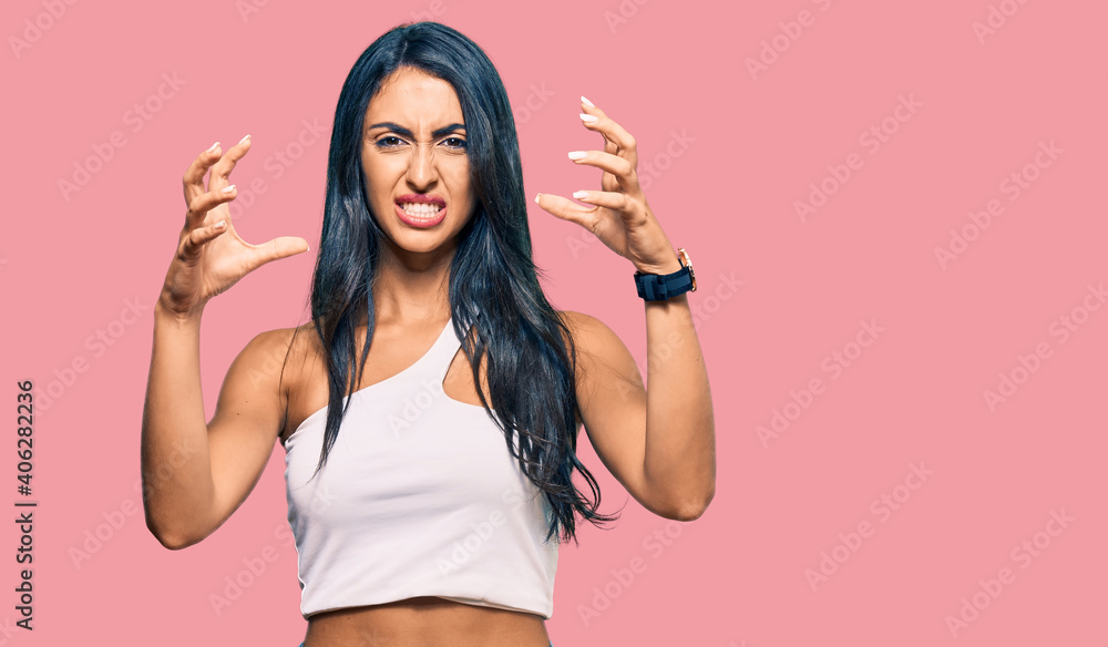 Beautiful hispanic woman wearing casual clothes shouting frustrated with rage, hands trying to strangle, yelling mad Beautiful hispanic woman wearing casual clothes shouting frustrated with rage, hands trying to strangle, yelling mad