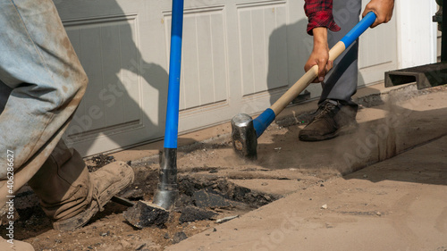 breaking up an asphalt driveway with a sledgehammer and a pickax 