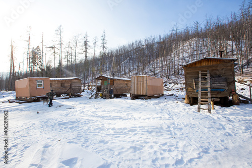 Wooden houses on the logging site in winter. Wooden technical and residential buildings in the deep taiga for co-workers of the timber industry complex.