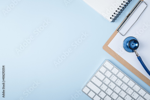 Doctor workplace. Stethoscope and computer keyboard on blue office desk top view copy space