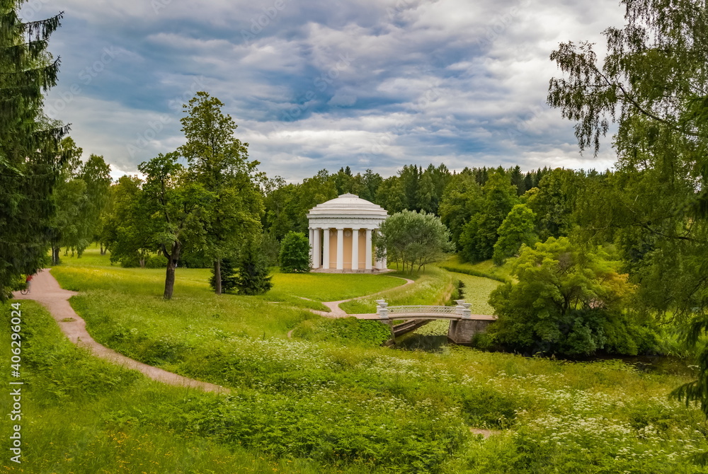 Summer landscape in the city Park with trees, pavilion, stone bridge over the river, sky with clouds