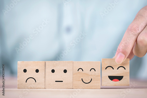 Obraz na plátne Businessman chooses a smiley face happy symbol on wooden block , Services and Cu
