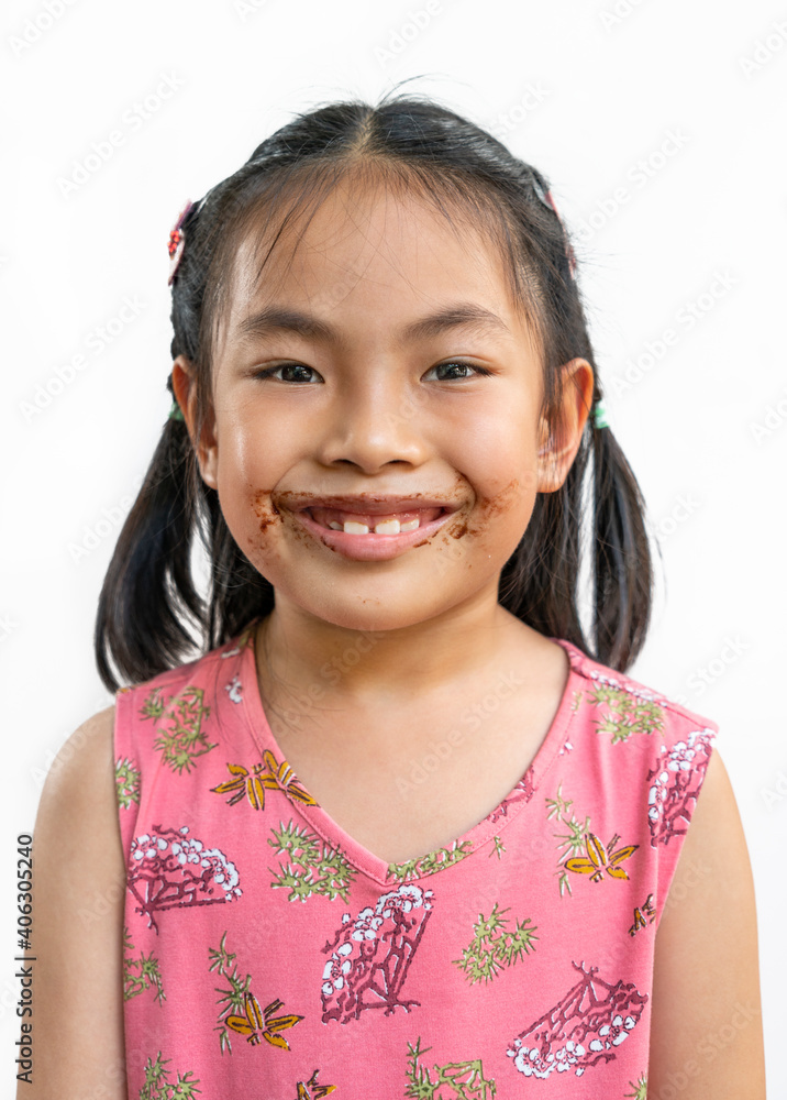 Portrait Asian cute child girl with messy of chocolate around her mouth, big smile on cute face, black hair, wearing beautiful pink dress, isolated image on white background with clipping path. Portrait Asian cute child girl with messy of chocolate around her mouth, big smile on cute face, black hair, wearing beautiful pink dress, isolated image on white background with clipping path.
