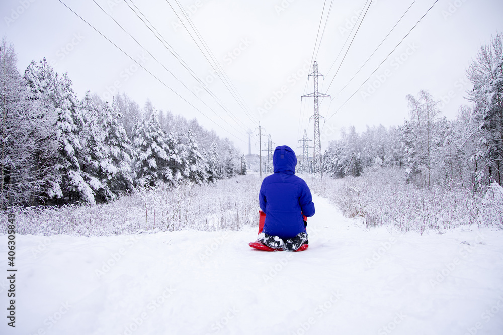 Lonely child skiing from a hill alone with beautiful snowy forest around. Winter sports and entertainment.