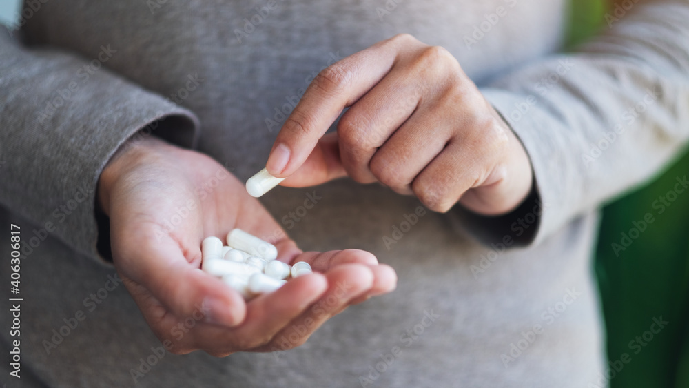 Closeup image of a woman holding and picking white medicine capsules in hand Closeup image of a woman holding and picking white medicine capsules in hand