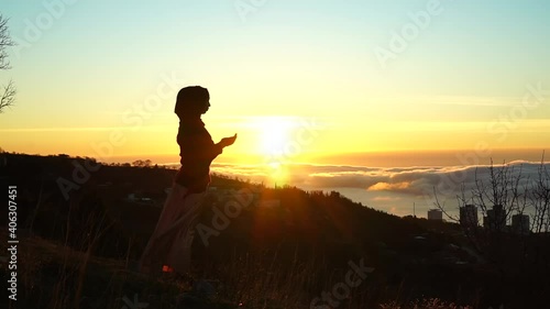 Muslim prayer. Silhouette of Muslim woman making Dua to Allah outdoor. Beautiful dawn, sunrise