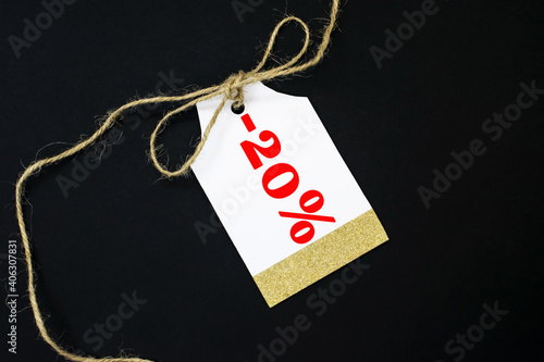 Sale tag with rope bow on black background. The tag says minus twenty percent. The concept of discounts photo