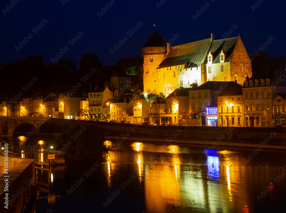 View from Mayenne river of illuminated castle and bridge of Laval town at summer night, southwestern France
